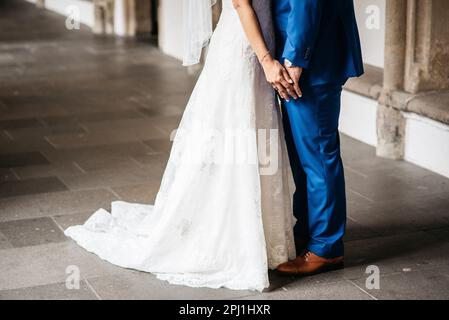 Un couple heureux et récemment ravi se tient dans une arcade devant un mur de briques, s'embrassant les uns les autres avec amour pendant qu'ils célèbrent leur Union Banque D'Images