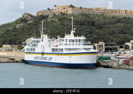 Un ferry traversant le canal de Gozo, qui est un court tronçon de la mer Méditerranée séparant l'île maltaise de Gozo de la pointe nord de Malte. Elle mesure environ 7 km (4,3 mi) de long et sa largeur varie de 6,7 km (4,2 mi) à son extrémité la plus large à 4,5 km (2,8 mi) à son extrémité nord-est Au centre du chenal se trouvent les deux îles de Comino (habitée) et Cominotto. Le canal sert de liaison maritime entre les deux îles avec un service de ferry dirigé par la ligne de canal Gozo qui fonctionne toute l'année depuis les ports de Mġarr Harbour et Ċirkewwa. Banque D'Images