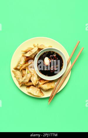 Assiette avec de savoureux jiaozi chinois et sauce sur fond vert Banque D'Images