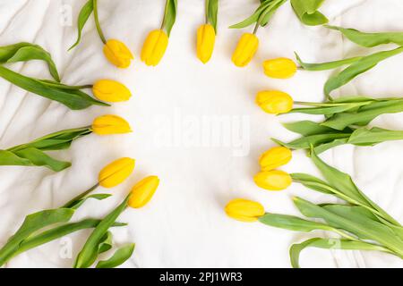 Les tulipes jaunes se trouvent sur une couverture blanche, à la lumière du jour, vue d'en haut Banque D'Images