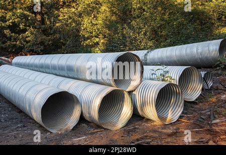 Tuyaux d'eaux pluviales. Grands tuyaux de ponceau en métal ondulé sur le terrain. Tube souple en aluminium ondulé, résistant aux températures élevées. Personne, sélectif Banque D'Images