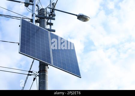 Panneaux solaires sur poteau lumineux de rue contre ciel nuageux, vue à angle bas. Espace pour le texte Banque D'Images