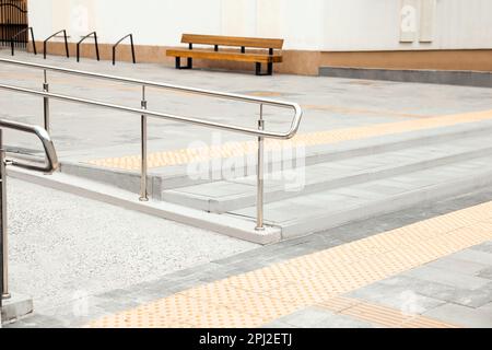 Escaliers extérieurs avec rampe, garde-corps en métal et carreaux tactiles. Accessibilité de l'environnement public Banque D'Images