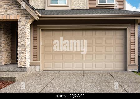 Porte de garage. Maison moderne avec porte de garage qui est fermée. Un quartier parfait. Maison familiale avec grande porte de garage et allée en béton devant. Banque D'Images