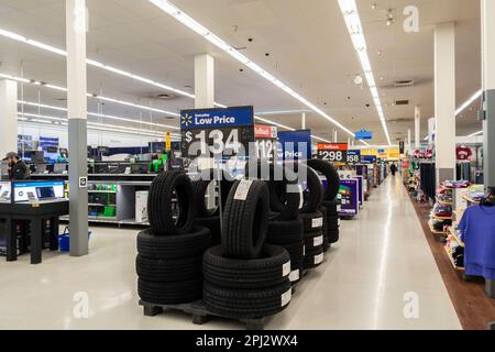 Une pile de pneus neufs dans une allée Walmart avec une affiche de bas prix. Intérieur, Wichita, Kansas, États-Unis. Banque D'Images