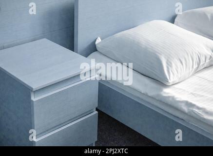 Teinte bleu clair, vue rapprochée du lit et de la table de chevet, intérieur moderne de la chambre à coucher de l'hôtel. Banque D'Images