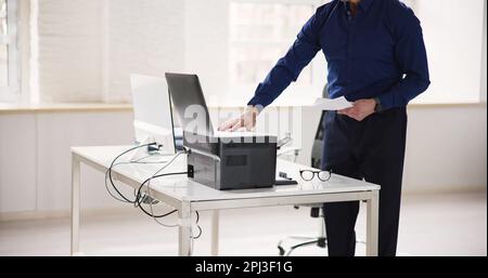 Homme utilisant une machine à photocopier dans Office. Imprimante et copieur Banque D'Images