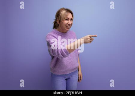 charmante blonde jeune femme millénaire dans un look décontracté pointant du doigt vers quelqu'un, se colant sur un arrière-plan lumineux avec espace de copie Banque D'Images