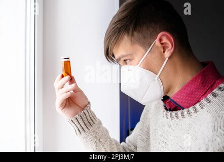 Jeune homme avec une pilule près de la fenêtre dans la chambre Banque D'Images