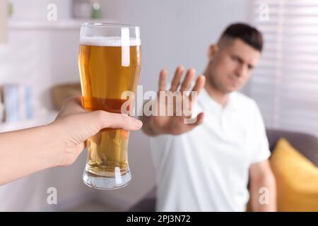 Homme refusant de boire de la bière dans la cuisine, gros plan. Traitement de la dépendance à l'alcool Banque D'Images