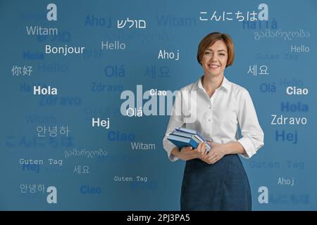 Portrait d'un traducteur heureux et de mots de bienvenue dans différentes langues étrangères sur fond bleu clair Banque D'Images