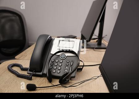 Téléphone fixe et casque sur un bureau en bois. Service d'assistance téléphonique Banque D'Images