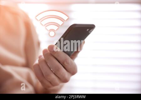 Homme utilisant un smartphone connecté au Wi-Fi en intérieur, gros plan Banque D'Images