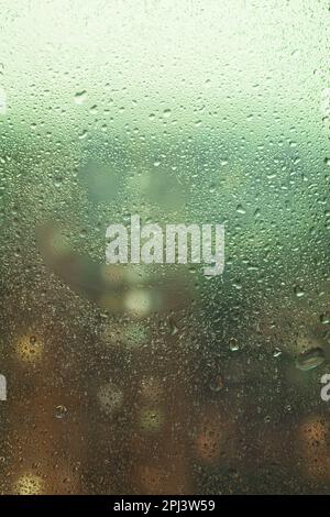 Gouttes de pluie sur le verre, grosses gouttes. Paysage avec gouttes de pluie tombant sur la fenêtre de la maison. Vue horizon floue. photo macro Banque D'Images