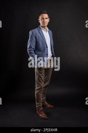 Homme d'affaires de bonne qualité avec les mains dans les poches sur fond sombre Banque D'Images