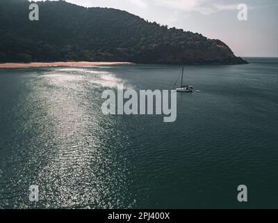 Vue aérienne d'un yacht blanc dans une petite baie sur une plage isolée Banque D'Images