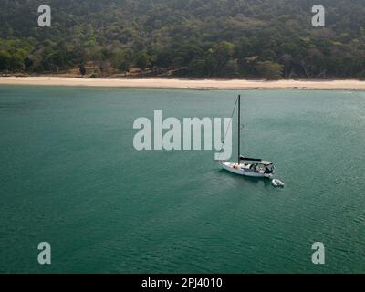 Vue aérienne d'un yacht blanc dans une petite baie sur une plage isolée Banque D'Images