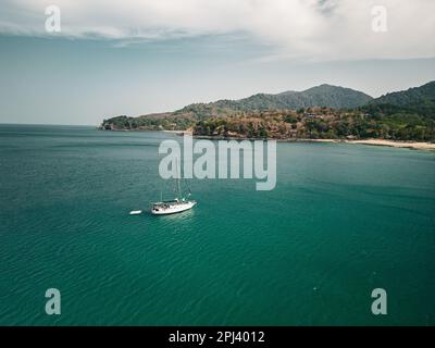 Vue aérienne d'un yacht blanc dans une petite baie sur une plage isolée Banque D'Images