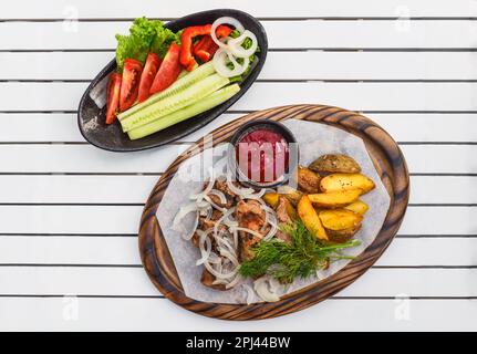 Shashlik de porc aux légumes grillés servi avec de la salade et du ketchup sur une planche de bois Banque D'Images