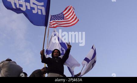 TEL AVIV, ISRAËL - MARS 30 : Un partisan du Premier ministre israélien Benjamin Netanyahu signe la victoire et garde le drapeau du Likoud alors que d'autres branchent et comptent le nombre de mandats que le parti Likoud a reçus lors des dernières élections lors d'un rassemblement en faveur de la coalition de droite israélienne et de ses propositions de changements judiciaires 30 mars 2023 à tel Aviv, Israël. Crédit : Eddie Gerald/Alay Live News Banque D'Images