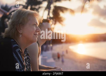 Portrait d'une femme âgée avec son fils adulte qui regarde ensemble la plage de sable et la mer au beau coucher du soleil. Banque D'Images