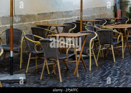 Vider la table et les chaises humides en bois sur la terrasse de la cafétéria extérieure sous la pluie. La vie urbaine dans la rue sous la pluie. Banque D'Images