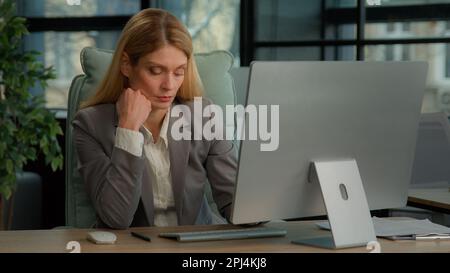Sérieuse fatiguée femme d'affaires exténuée caucasienne d'âge moyen femme orientée femme directrice exécutive assis à un bureau travaillant dactylographiant un ordinateur Banque D'Images