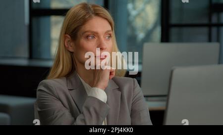 Caucasien pensive adulte 40s femme assis au bureau moderne de travail sur ordinateur portable faire un travail en ligne freelance. Femme d'affaires d'âge moyen Banque D'Images