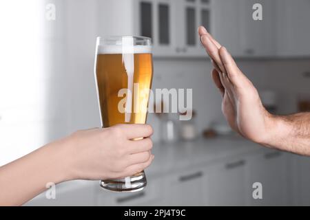 Homme refusant de boire de la bière dans la cuisine, gros plan. Traitement de la dépendance à l'alcool Banque D'Images