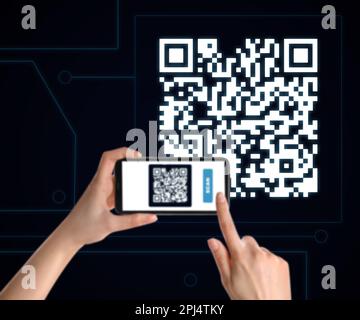 Femme scannant un code QR avec un smartphone sur fond noir, gros plan Banque D'Images