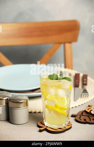 Verre de limonade et dessous de verre en forme de feuilles sur table en bois gris Banque D'Images