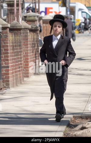 Un adolescent juif hassidique marchant avec ses mains dans ses poches lors d'une journée froide au début du printemps. À New York. Banque D'Images