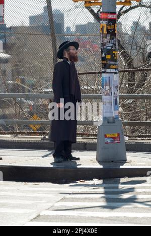 Un juif orthodoxe habillé en noir lit des affiches et des annonces principalement en yiddish avec un peu d'hébreu. À Brooklyn, New York. Banque D'Images