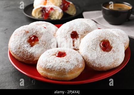 Délicieux beignets avec gelée et sucre en poudre sur table noire, gros plan Banque D'Images