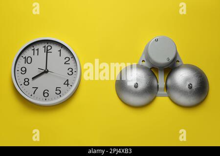 Horloge et cloche électriques modernes sur le mur jaune Banque D'Images