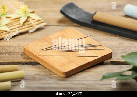 Planche avec aiguilles d'acupuncture sur table en bois Banque D'Images