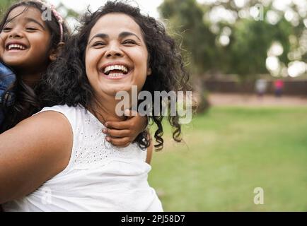 Bonne mère indienne s'amuser avec sa fille à l'extérieur - famille, fête de maman et concept d'amour - Focus sur le visage de maman Banque D'Images