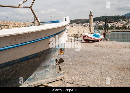 Le port et le phare de Réthymnon, en Crète, en Grèce, où les bateaux de pêche sont attachés et certains sont transportés hors de l'eau. Banque D'Images