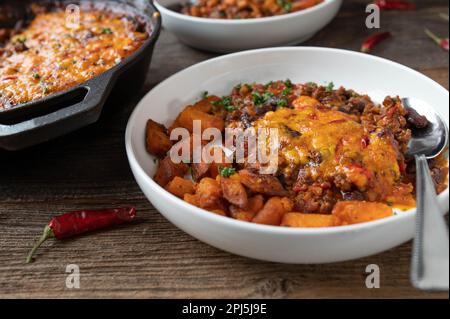 Ragoût de haricots avec bœuf haché, garniture au fromage cheddar gratiné et patates douces rôties Banque D'Images