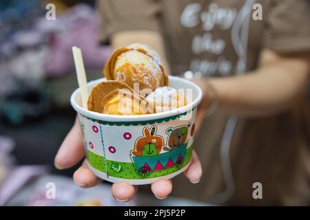 Une cuisine de rue dans Chinatown à Bangkok en Thaïlande, en vue d'une coupe avec une spécialité sucrée se tient dans une main. Banque D'Images