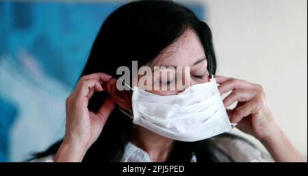 Femme plus âgée mettant le masque de prévention du virus, portrait d'une femme âgée de 50 ans portant un masque pandémique Banque D'Images