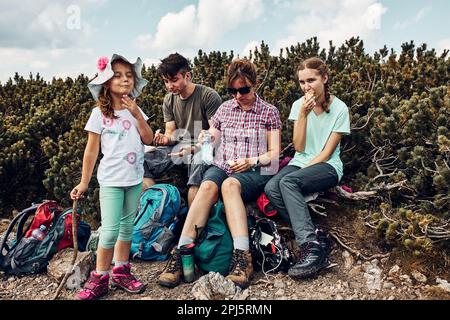 Famille en vacances et en-cas pendant le voyage en montagne. La famille passe activement des vacances d'été ensemble. Mère avec ses enfants adolescents Banque D'Images