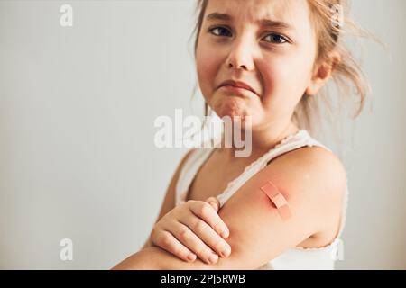 Petite fille sensation de douleur ayant quelques effets secondaires après la vaccination. Rougeur, enflure, membres de la douleur et maux de tête comme réaction après la vaccination. Getti Banque D'Images