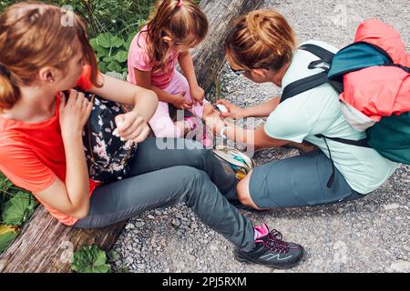 Mère portant la plaie sur le genou de sa petite fille avec un médicament en spray. Un accident s'est produit lors d'un voyage de vacances d'été en famille. Les gens activement Banque D'Images