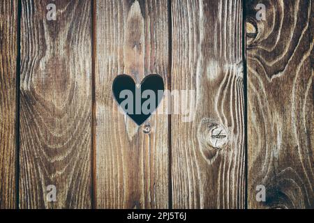 Porte en bois avec trou en forme de coeur. Arrière-plan de texture bois. Ancienne surface de planche rustique Banque D'Images