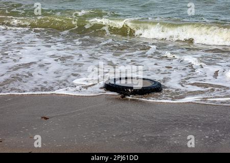 Plage mexicaine avec un pneu de voiture couché sur le sable avec l'eau de mer en arrière-plan, de petites vagues s'écrasant sur la côte côtière, jour ensoleillé au Mexique. Environnement Banque D'Images