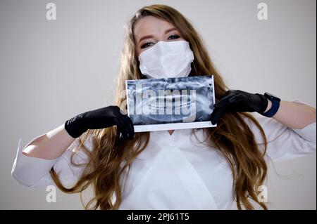 Radiographie d'une mâchoire humaine dans les mains du dentiste radiographie panoramique des dents humaines. Le dentiste tient une photo panoramique de rayons X dans ses mains en gants médicaux jaunes dentistes chirurgie. Haute qualité Banque D'Images