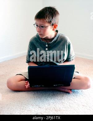 School from home A Young boy intently studying his laptop Stock Photo