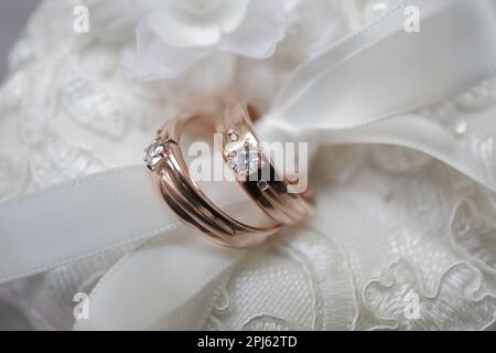 Paire d'anneaux de mariage or rose avec diamant attaché dans un tissu blanc Banque D'Images