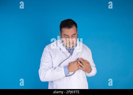 Le médecin vérifie son cœur avec un stéthoscope sur fond bleu isolé. concept de santé préventive Banque D'Images